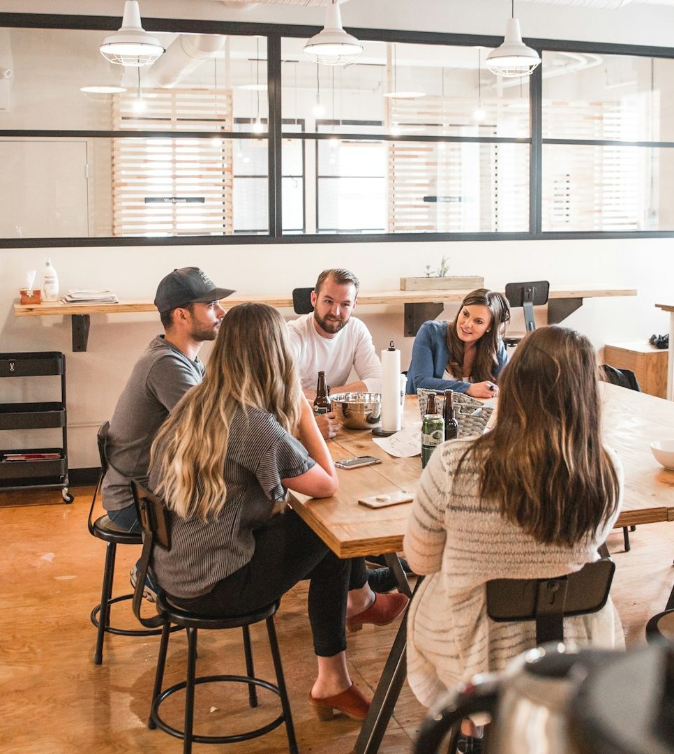 group stock photo Two men and three women sitting at a table while discussing ideas